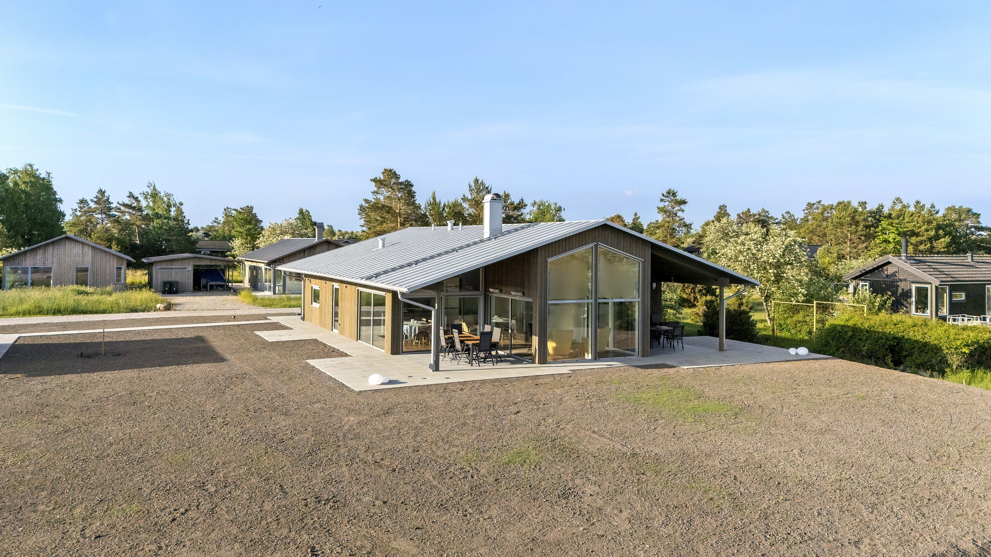 Nybyggt enplanshus med träfasad och stora fönster på en grusad tomt, byggt av G-Bygg